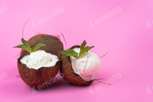 Preview: Vanilla ice cream balls in fresh coconut halves decorated with mint leaves on a pink background