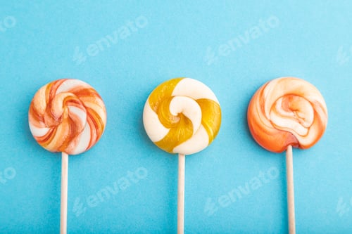 Preview: Three lollipop candies on blue background. copy space, top view