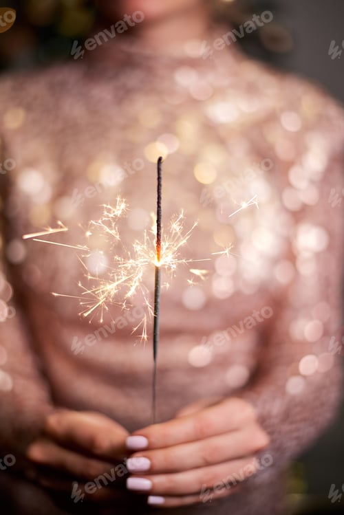 Preview: Young woman holding sparkler in hands