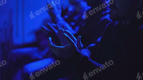 Preview: Close-up of audience applauding performance in dark hall. Media. Audience attentively watches and