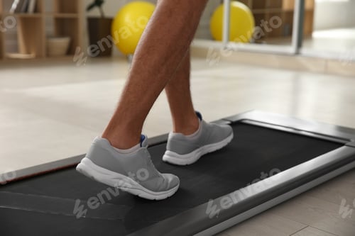 Preview: Sporty man training on walking treadmill at home, closeup