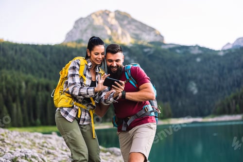 Preview: Couple Checking Smartphone by Mountain Lake