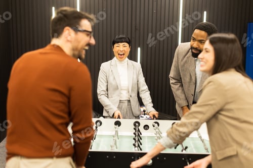 Preview: Engaging group enjoys a lively foosball game in a modern creative space