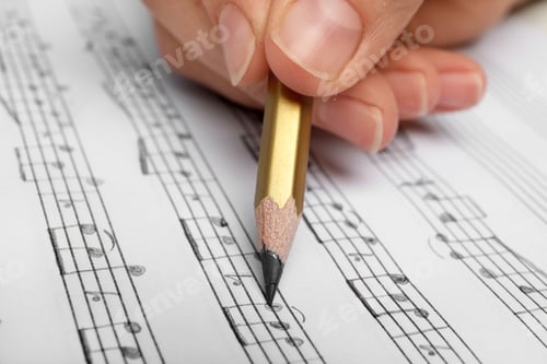 Preview: Woman writing music notes on sheet with pencil, closeup