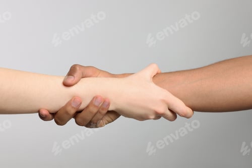 Preview: International relationships. People holding hands on light grey background, closeup