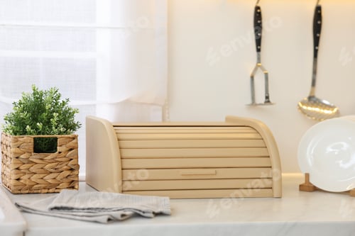Preview: Wooden bread box, houseplant and plates on white marble countertop in kitchen