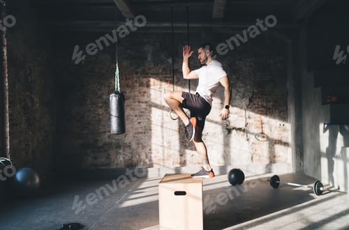 Preview: Strong man doing box jump exercise at gym during fitness training