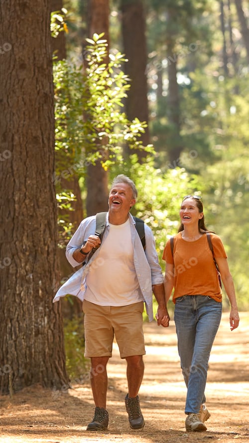 Preview: Senior Retired Couple Holding Hands Hiking Along Trail In Countryside