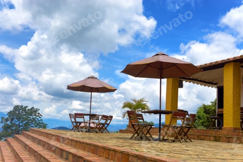 Preview: Outdoor Cafe Tables with Umbrellas Under Blue Skies