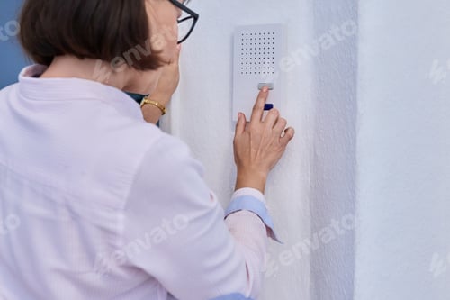 Preview: Woman using intercom inside the house, closeup