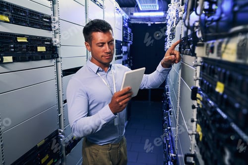 Preview: IT technician consulting tablet computer during preventive maintenance