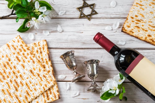 Preview: Jewish religious holiday of Passover. Bottle of wine, matzo and flowers on white wooden background.