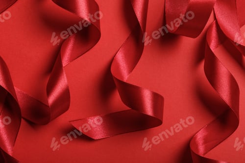 Preview: close up of curved satin red ribbons on red background