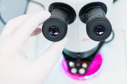 Preview: Close up scientist hand sets up a microscope to analyze the sample