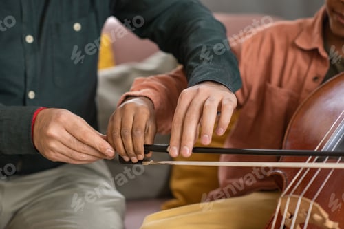 Preview: Hands of music teacher and his pupil playing cello