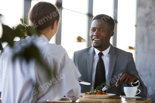 Preview: Black man talking to business partner over lunch