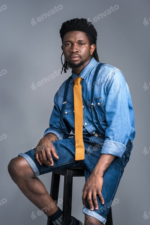 Preview: handsome african american man sitting on chair isolated on gray