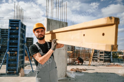 Preview: Front view. Carrying wooden plank. Man in uniform is working on the construction site