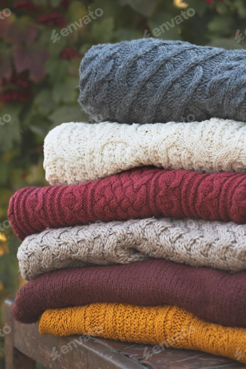 Preview: Stack of Colorful Knitted Sweaters on Wooden Bench