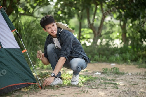 Preview: Man Pitches Tent while Camping in Rural Location