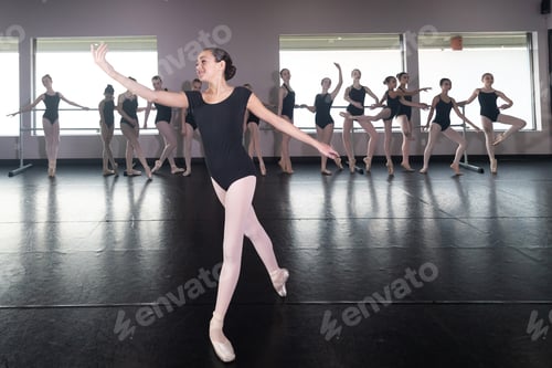 Preview: Teenage girl in ballet dance studio poses with the rest of the class behind her
