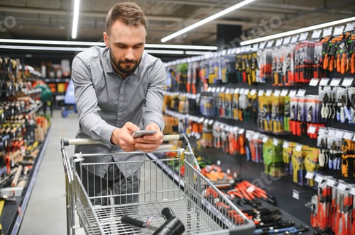 Preview: male builder in a hardware store chooses a tools