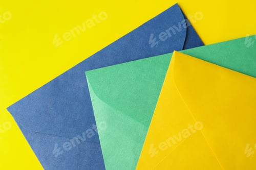 Preview: Colorful paper envelopes on yellow background, top view