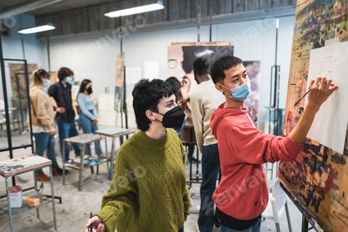 Preview: Multiracial students painting inside art room class wearing safety masks - Focus on boy back