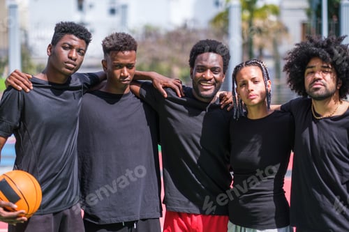 Preview: Young friends with urban style playing basketball on multicolored court