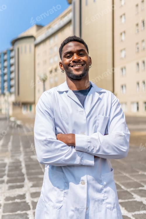 Preview: Smiling african doctor standing with arms crossed outside the hospital