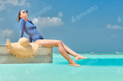 Preview: Woman sitting at beach jetty