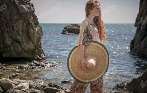 Preview: attractive young woman in ethnical costume on a field at sea