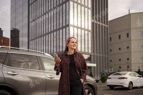 Preview: Woman stand speak use phone in city near gray car