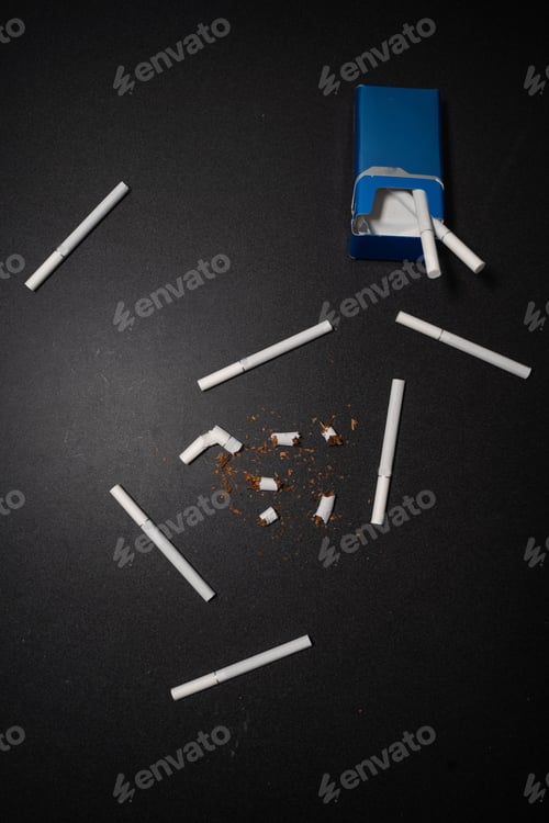Preview: Vertical shot of broken cigarettes isolated on a black background - stop smoking concept