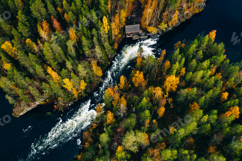 Preview: Aerial view of fast river with suspension foot bridge and wooden cabin in autumn forest.