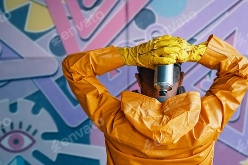 Preview: Cropped image of street artist with spray paint can in hand standing near the wall