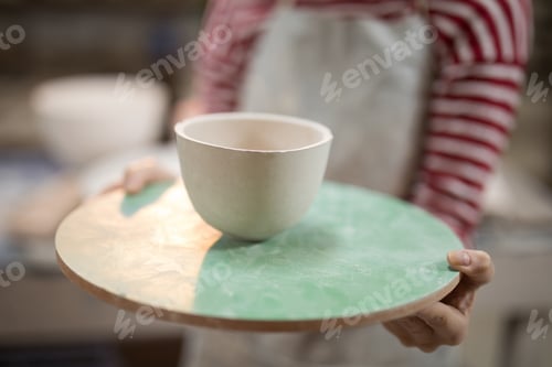 Preview: Mid section of female potter holding bowl