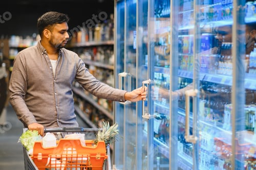 Preview: Young man choosing products from supermarket refrigerator