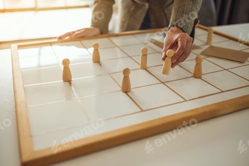 Preview: Businesswoman leader choosing wooden people from a group of employees on a planning board