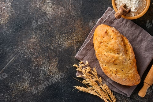 Preview: Homemade bread with seeds on a wooden stand, wheat flour and ears on brown old concrete background t