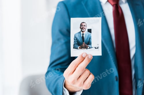 Preview: cropped view of recruiter touching photo with african american man in glasses