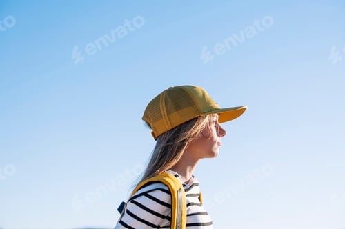 Preview: Outdoor portrait of a beautiful young blonde woman in a yellow cap and a bracket on her teeth.
