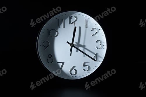 Preview: Closeup of a white clock showing twelve 20 on a dark background