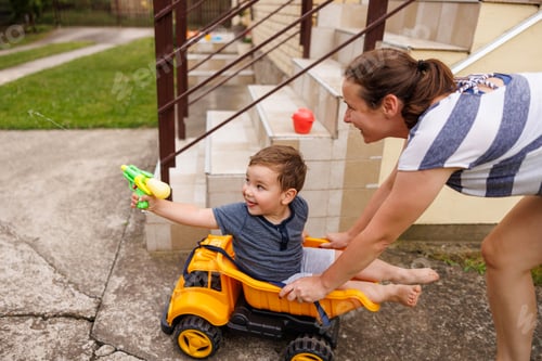 Preview: Mother having fun pushing child in toy truck