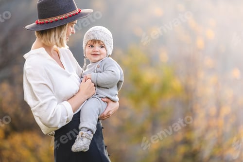 Preview: Mother in a hat with a small child having fun on a walk together in autumn