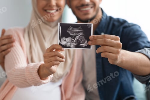 Preview: Closeup shot of happy pregnant muslim couple demonstrating baby sonography photo