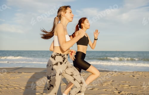 Preview: Young athletic women in sportswear is jogging along shore of beach. Concept of healthy living