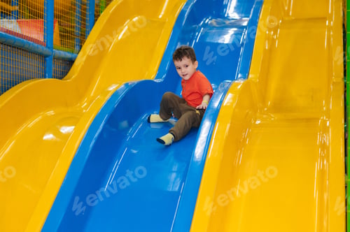 Preview: A boy rides from the children's slides on the playground in the play center. Active leisure
