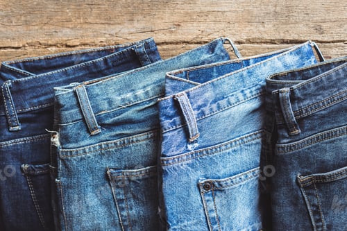 Preview: Jeans stacked on a wooden background