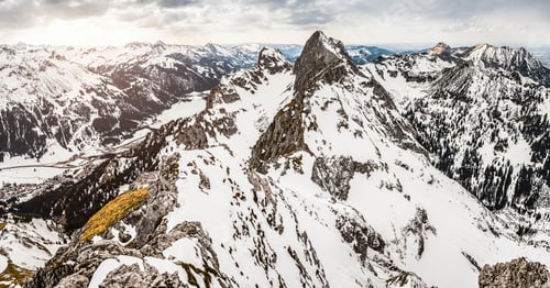 Preview: Breathtaking panoramic view of a snowcapped mountain range under a cloudy sky